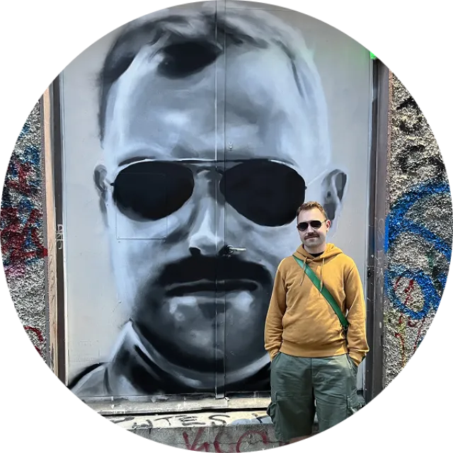 Jamie, standing in front of a mural of Jamie, painted by Oriel.
