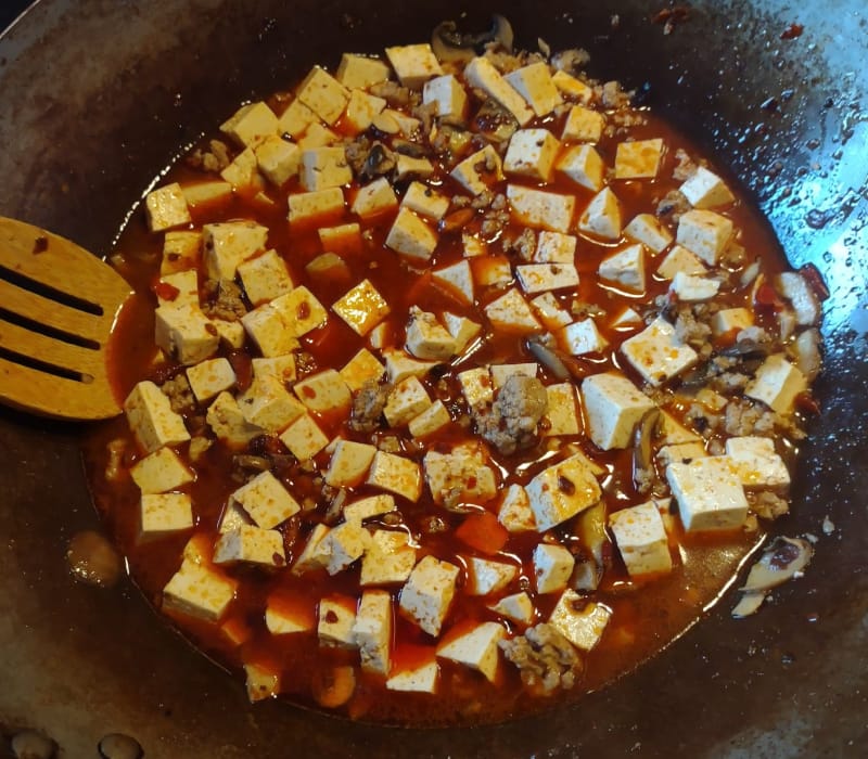 Photo of mapo tofu inside a large wok.